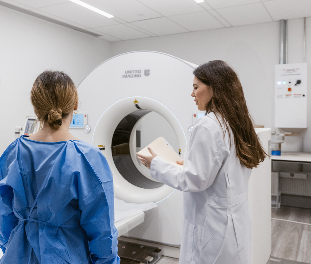 Medical staff member reviewing patient charts and preparing a patient for advanced diagnostic imaging scan